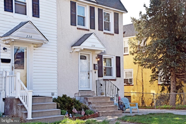 multi unit property featuring stucco siding, fence, and a shingled roof