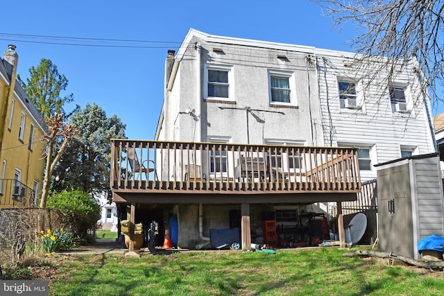 rear view of property featuring a yard, stucco siding, a deck, and a chimney
