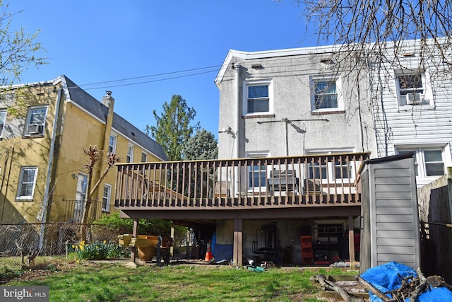 rear view of property featuring a deck, stucco siding, and fence