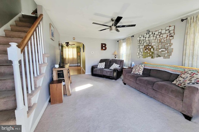 living room with baseboards, arched walkways, ceiling fan, carpet, and stairs