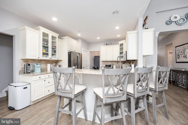 13115 Muirfield Ln, Berlin, MD 21811 - kitchen featuring light wood-style floors, glass insert cabinets, a peninsula, stainless steel fridge, and backsplash