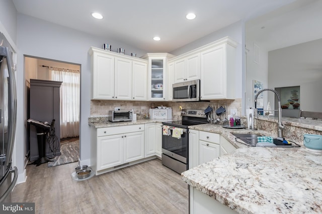 13115 Muirfield Ln, Berlin, MD 21811 - kitchen featuring glass insert cabinets, light wood-style flooring, tasteful backsplash, appliances with stainless steel finishes, and a sink