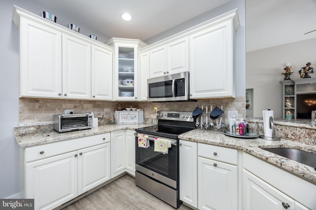 13115 Muirfield Ln, Berlin, MD 21811 - kitchen featuring decorative backsplash, white cabinetry, light stone countertops, and stainless steel appliances