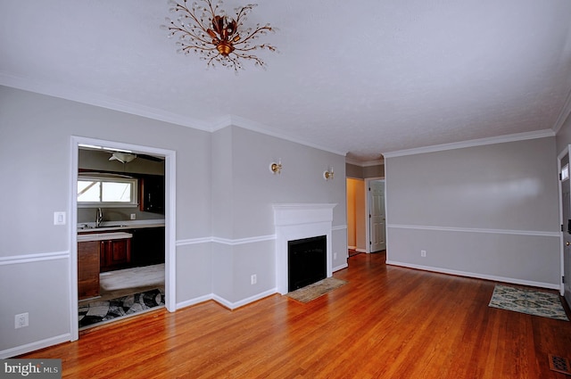 unfurnished living room featuring a fireplace with flush hearth, baseboards, crown molding, and light wood-type flooring