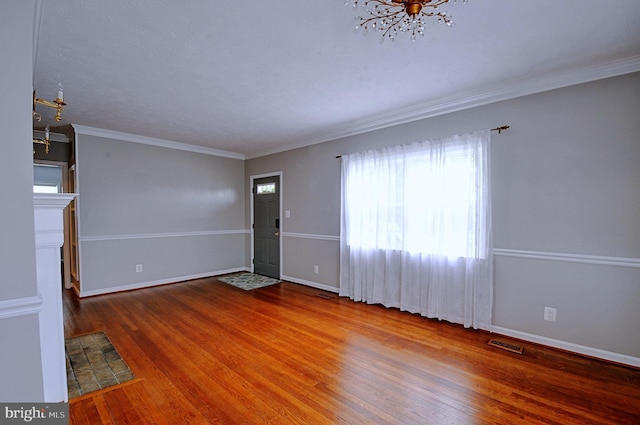 interior space featuring visible vents, baseboards, an inviting chandelier, wood finished floors, and crown molding
