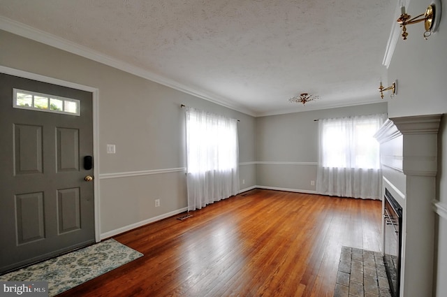 foyer featuring crown molding, a healthy amount of sunlight, wood finished floors, and visible vents