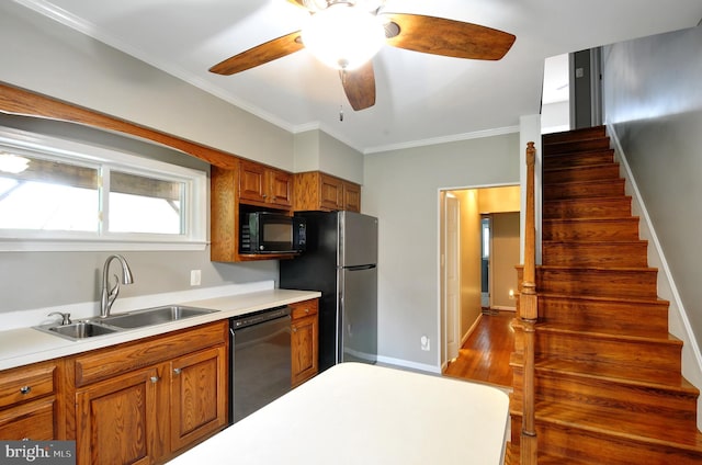 kitchen featuring a sink, brown cabinetry, black appliances, ceiling fan, and light countertops