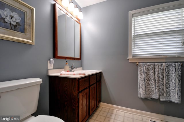 half bath featuring baseboards, vanity, and toilet