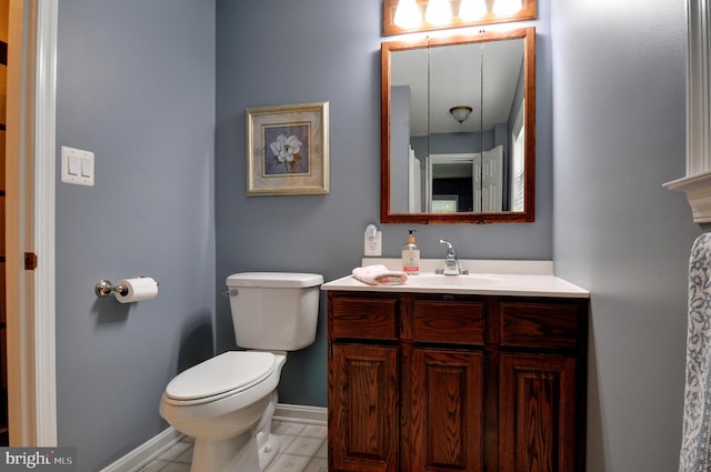 bathroom with baseboards, vanity, and toilet