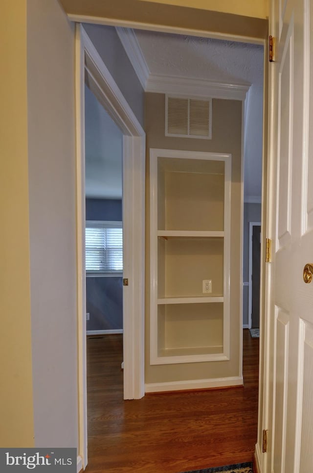 corridor with baseboards, visible vents, dark wood-style floors, and ornamental molding