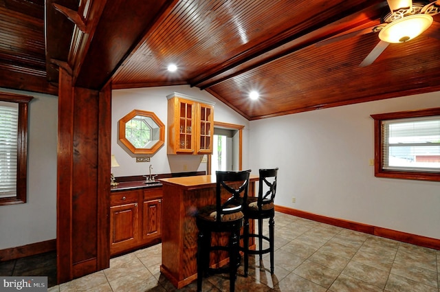 bar featuring wooden ceiling, indoor wet bar, light tile patterned floors, and baseboards
