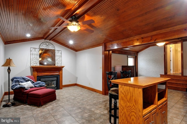 interior space featuring a glass covered fireplace, vaulted ceiling with beams, baseboards, and a ceiling fan