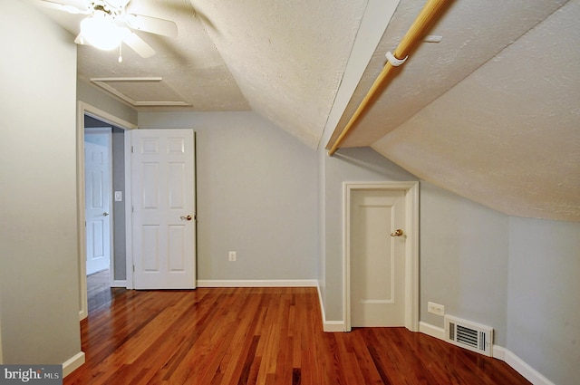 bonus room with vaulted ceiling, wood finished floors, a textured ceiling, baseboards, and visible vents