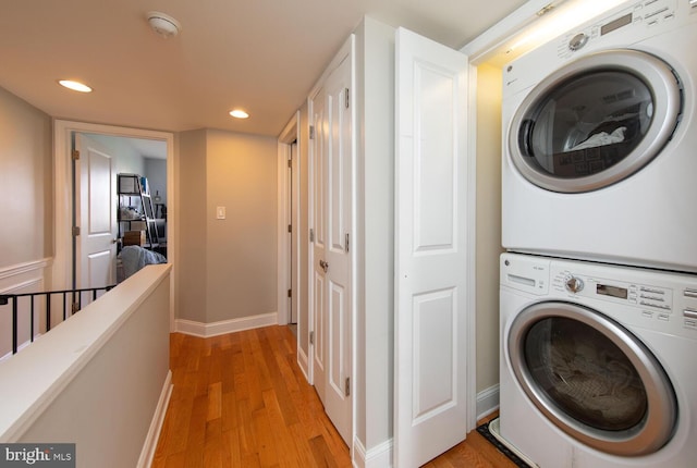 laundry room with stacked washing maching and dryer, light wood-style flooring, laundry area, baseboards, and recessed lighting
