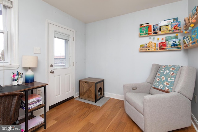 sitting room with baseboards and light wood finished floors