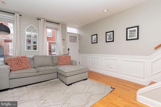 living room with plenty of natural light, wood finished floors, recessed lighting, and a wainscoted wall