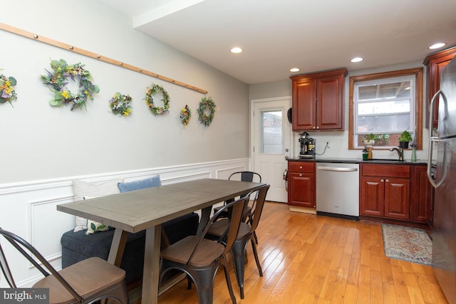 kitchen featuring a wainscoted wall, light wood-style flooring, a healthy amount of sunlight, and appliances with stainless steel finishes