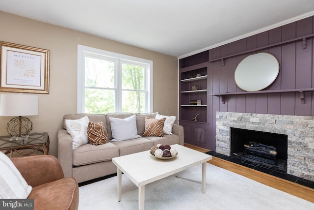 7012 Lancaster Rd, Baltimore, MD 21207 - living room featuring light wood-style floors, built in shelves, and a stone fireplace