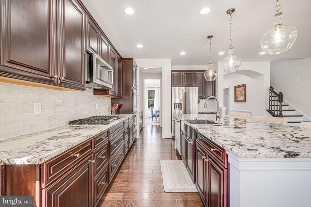24642 Black Willow Dr, Aldie, VA 20105 - kitchen featuring dark wood finished floors, arched walkways, appliances with stainless steel finishes, a sink, and decorative backsplash