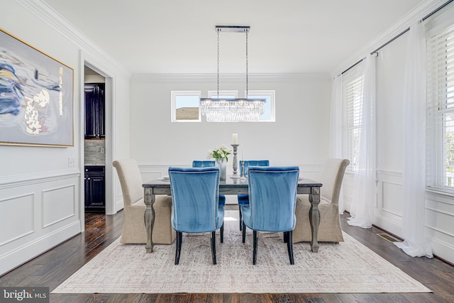 24642 Black Willow Dr, Aldie, VA 20105 - dining space with crown molding, a decorative wall, a wainscoted wall, dark wood-style flooring, and a notable chandelier