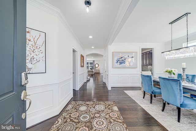 24642 Black Willow Dr, Aldie, VA 20105 - entrance foyer featuring crown molding, a decorative wall, an inviting chandelier, dark wood-type flooring, and arched walkways