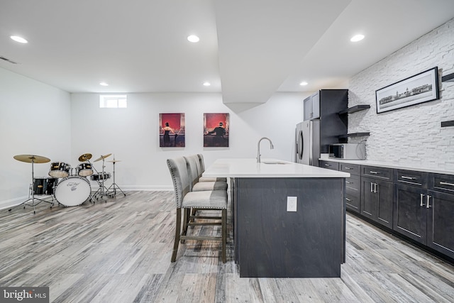 24642 Black Willow Dr, Aldie, VA 20105 - kitchen with stainless steel fridge with ice dispenser, a sink, an island with sink, a kitchen bar, and light wood finished floors