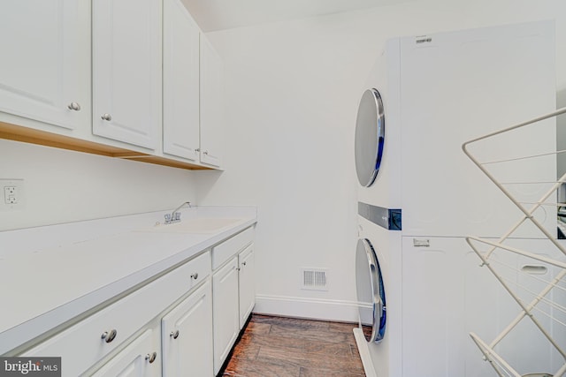 24642 Black Willow Dr, Aldie, VA 20105 - washroom with stacked washer and dryer, dark wood-style floors, visible vents, cabinet space, and a sink