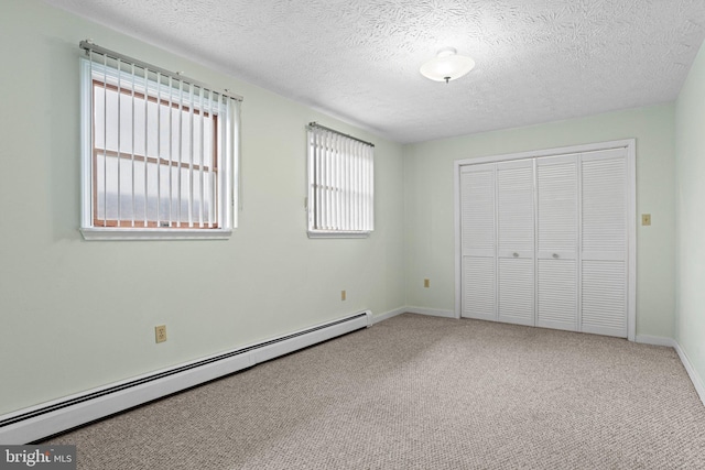 unfurnished bedroom with a textured ceiling, a closet, carpet floors, a baseboard heating unit, and baseboards