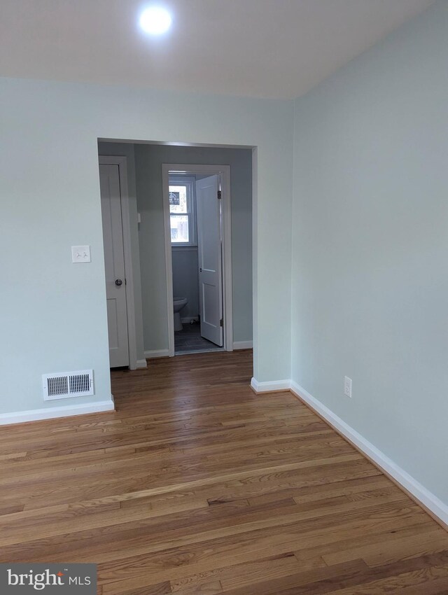unfurnished room with baseboards, visible vents, and wood finished floors