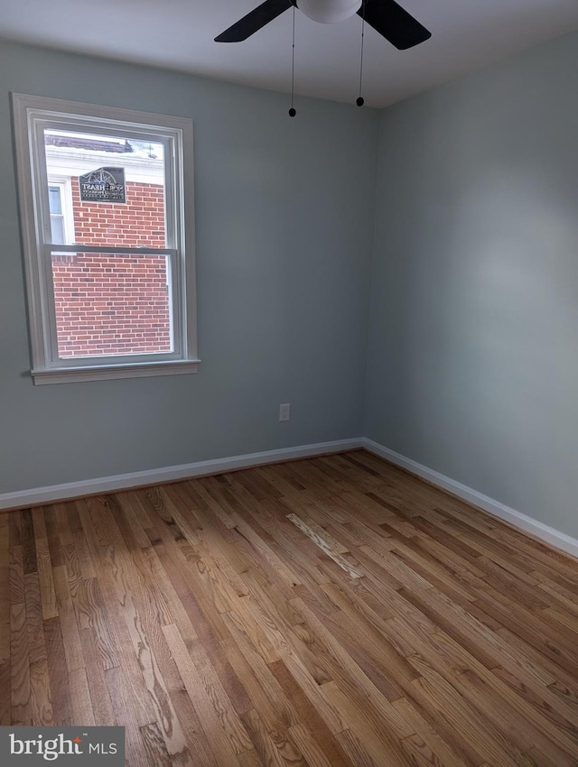 spare room with baseboards, wood finished floors, and a ceiling fan