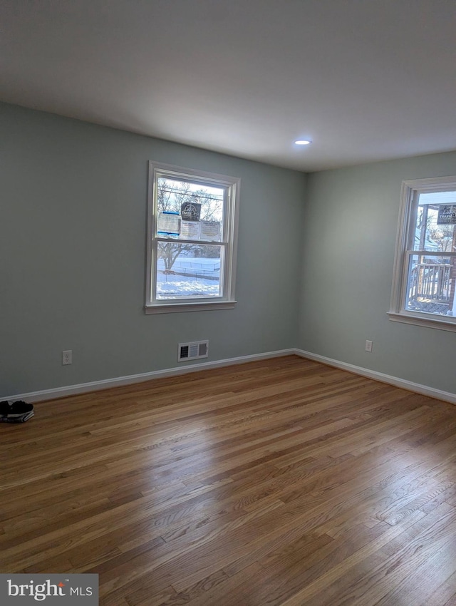 empty room featuring wood finished floors, recessed lighting, baseboards, and visible vents