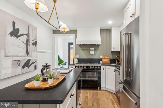 1129 E Berks St, Philadelphia, PA 19125 - kitchen with light wood finished floors, dark countertops, high end appliances, premium range hood, and white cabinetry