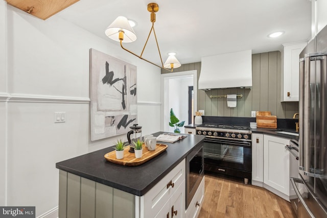 1129 E Berks St, Philadelphia, PA 19125 - kitchen with dark countertops, premium range hood, a sink, light wood-style floors, and high quality appliances