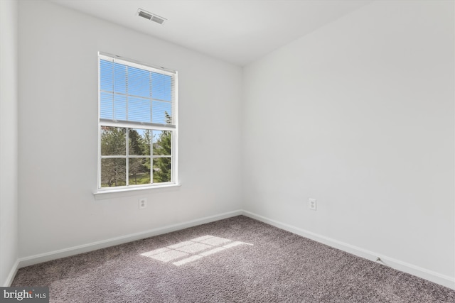 empty room featuring carpet floors, visible vents, and baseboards
