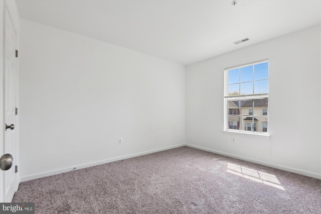 spare room with baseboards, visible vents, and carpet