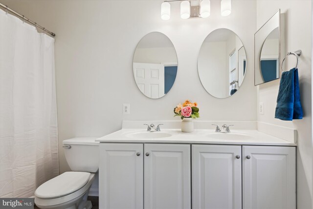 full bathroom featuring toilet, a sink, and double vanity