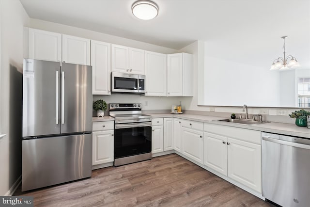 kitchen with a sink, a chandelier, white cabinetry, light countertops, and appliances with stainless steel finishes