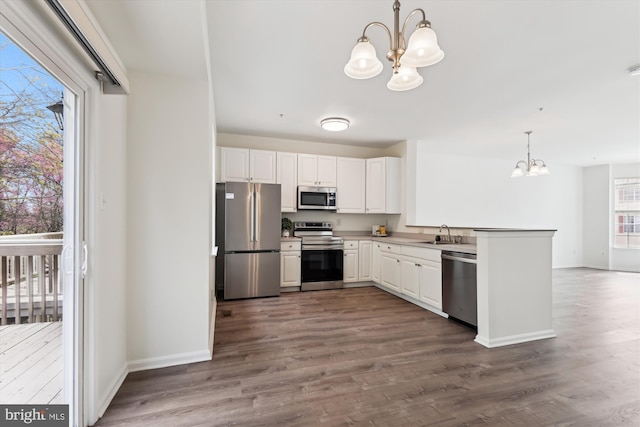 kitchen featuring a sink, baseboards, stainless steel appliances, and an inviting chandelier