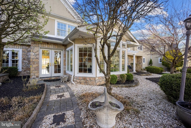 property entrance featuring french doors, stucco siding, and stone siding