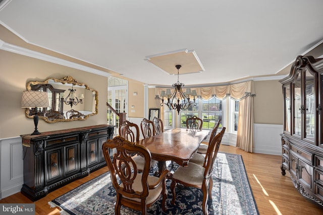dining room with a chandelier, a decorative wall, wainscoting, and ornamental molding