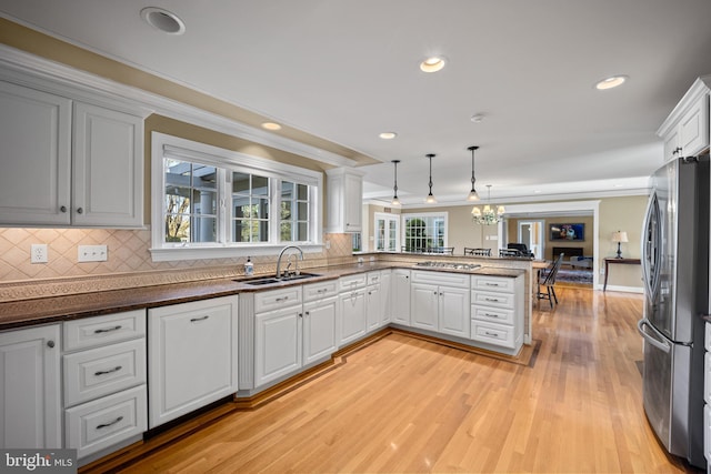 kitchen with a sink, a peninsula, recessed lighting, stainless steel appliances, and light wood-style flooring