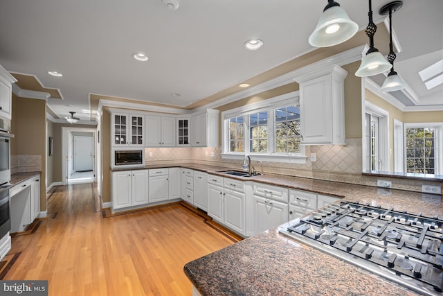 kitchen with stainless steel appliances, white cabinetry, a sink, and ornamental molding