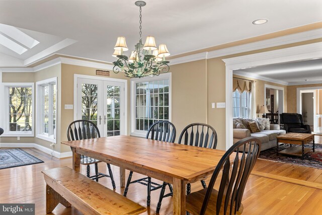 dining room with french doors, baseboards, light wood-type flooring, and a chandelier