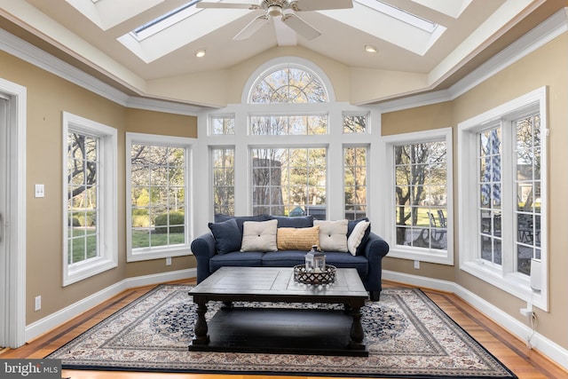 sunroom featuring baseboards, lofted ceiling with skylight, and wood finished floors