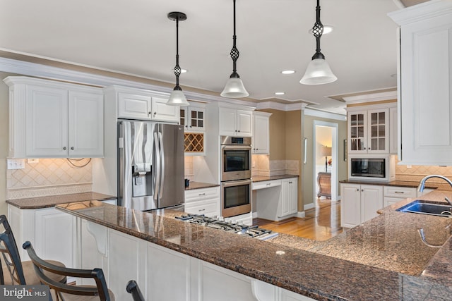 kitchen with glass insert cabinets, ornamental molding, a sink, stainless steel appliances, and backsplash