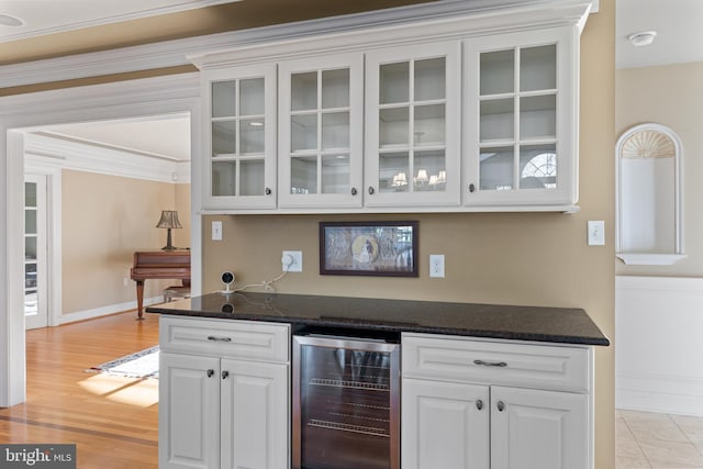 bar with light wood-style flooring, baseboards, and beverage cooler