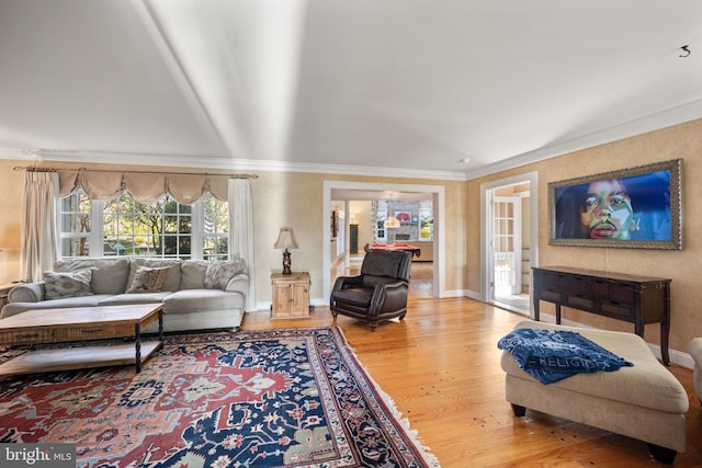 living room featuring crown molding, baseboards, and wood finished floors