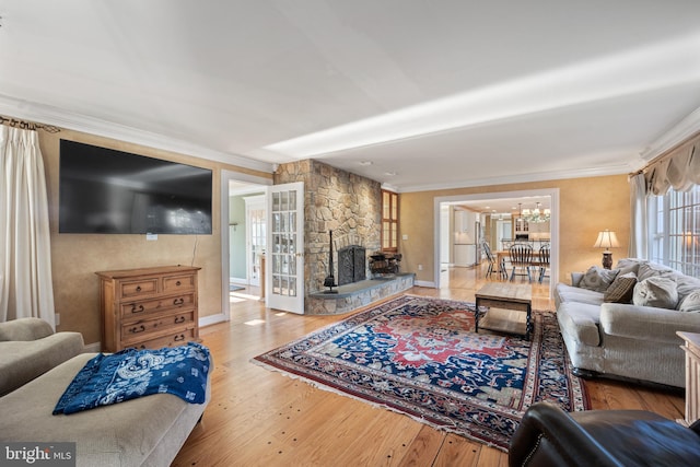 living room with crown molding, baseboards, an inviting chandelier, and hardwood / wood-style floors