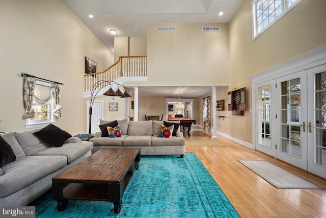living area featuring wood finished floors, decorative columns, and a towering ceiling