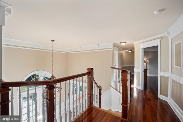 hall with an upstairs landing, ornamental molding, and wood finished floors